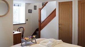 Une chambre à coucher avec un lit, un escalier en bois, une porte en bois et une fenêtre.