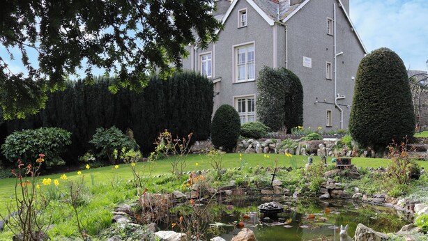 Un jardin avec un étang, des rochers et un panneau sur lequel on peut lire « BRYN ».