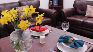 Une table à manger agrémentée d’un vase de fleurs jaunes, d’une bougie et d’un verre à vin.