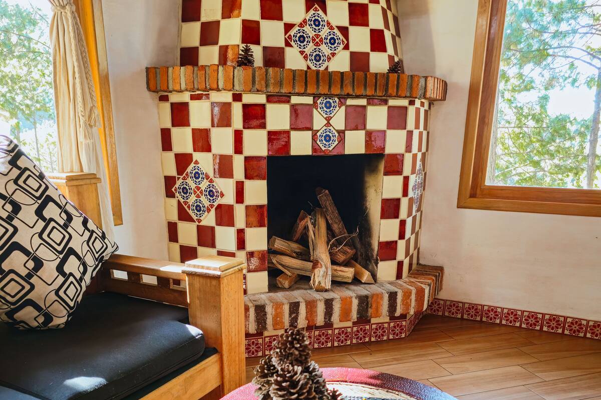 Een gezellige woonkamer met een schouw met ruitpatroon, een bank en een salontafel met een dennenappel als decoratie.