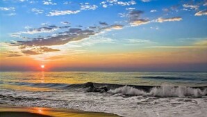Een strand met golven bij zonsondergang.