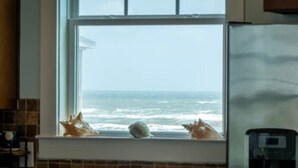 Een keuken met een groot raam met uitzicht op de oceaan.