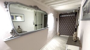 A hallway with a large mirror, a small table, and patterned wallpaper. - Junior Suite Deluxe per Due, Corso Italia 114 (Arezzo)