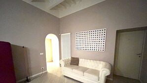 A room with a white sofa, a radiator, a door, and a wall with a grid pattern. - Junior Suite Deluxe per Due, Corso Italia 114 (Arezzo)