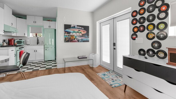 A modern kitchen with white cabinets, a green refrigerator, and a vintage poster on the wall. - Sunset Bungalows Lil' Green: Heated Pool, Near Beach & DT, Fenced (Clearwater)