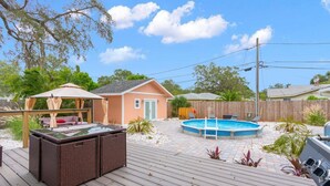 A backyard with a hot tub, a wooden deck, and a small house. - Sunset Bungalows Lil' Green: Heated Pool, Near Beach & DT, Fenced (Clearwater)
