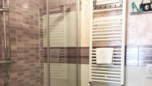 Une salle de bain dotée d’une douche à parois de verre, d’un bidet et d’un porte-serviettes.