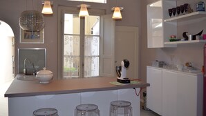 Une cuisine moderne dotée d’un îlot central, de luminaires suspendus et offrant une vue à travers une porte vitrée.