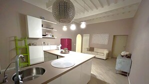 Une cuisine moderne dotée d’un îlot central, d’un évier encastré et d’un luminaire suspendu.