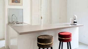 Une cuisine moderne dotée d’un îlot central, de deux tabourets, d’un évier et d’un four à micro-ondes.