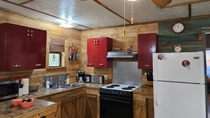 Una cocina con armarios de madera, estufa, refrigerador y ventilador de techo.