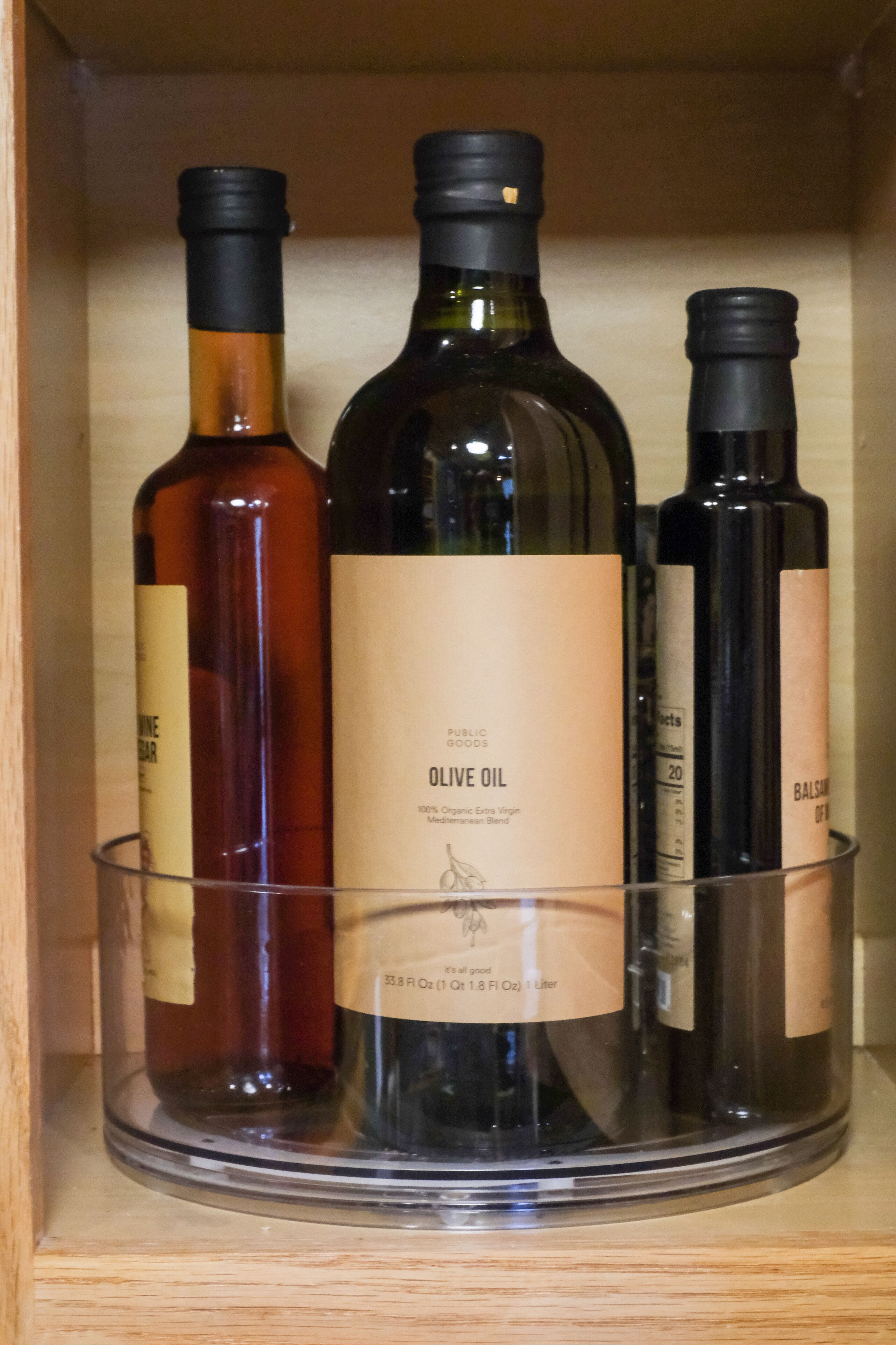 Un armario de madera con tres botellas de aceite de oliva.