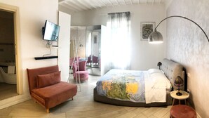 Quarto com cama, sofá, televisão e espelho.