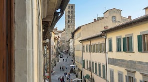 A narrow street with buildings on either side, a prominent tower in the background, and people walking. - Suite deluxe Corso Italia 114 (Arezzo)