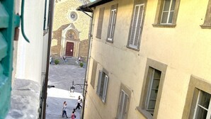 Rua estreita com edifícios de ambos os lados, uma igreja com uma entrada imponente e pessoas a passear.