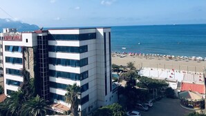 A hotel with a modern design, located near a beach with umbrellas and a carousel. - Syphax Tichy Plage (Tichy)