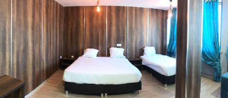 A hotel room with a large bed, two bedside tables, and a small desk.
