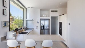 Una cocina moderna con una isla grande, electrodomésticos de acero inoxidable y vistas al exterior.