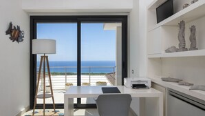 Una habitación moderna con balcón, escritorio, silla, lámpara y elementos decorativos.