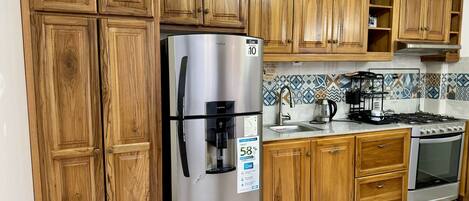 Une cuisine avec des meubles en bois, un réfrigérateur en acier inoxydable, une cuisinière à gaz et un four encastré.