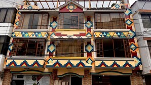 A multi-story building with colorful geometric patterns on the facade, multiple balconies, and a sign indicating legal services.
