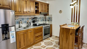 A kitchen with wooden cabinets, a stainless steel refrigerator, a gas stove, and a dining table with chairs.