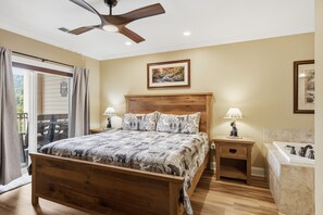 Un dormitorio con una cama de madera, dos lámparas de noche, un ventilador de techo y un cuadro en la pared.