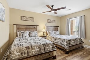 A bedroom with two beds, a ceiling fan, and a window with blinds.