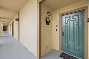 Un pasillo de hotel con una puerta verde, felpudo y un cartel sobre la puerta.