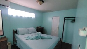 Un dormitorio con cama, mesita de noche, inodoro empotrado y puerta.