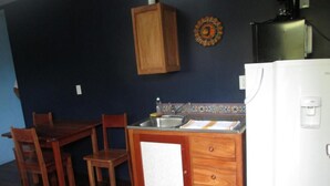Cocina compacta con muebles de madera, un lavabo y un refrigerador.