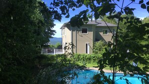 A house with a swimming pool surrounded by lush greenery. - Charming Home, Panoramic Mountain Views, Ideal For Family (Bolton-Ouest)