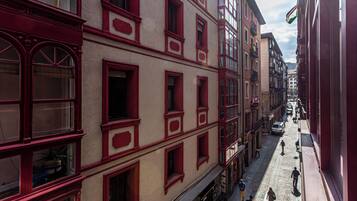 A narrow street with buildings featuring red window frames and multiple stories.