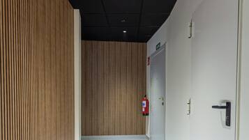 A corridor with wooden panel walls, a fire extinguisher, and a door with a handle.