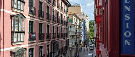 Una calle estrecha flanqueada por edificios con balcones, y un letrero que dice 'Pension'.