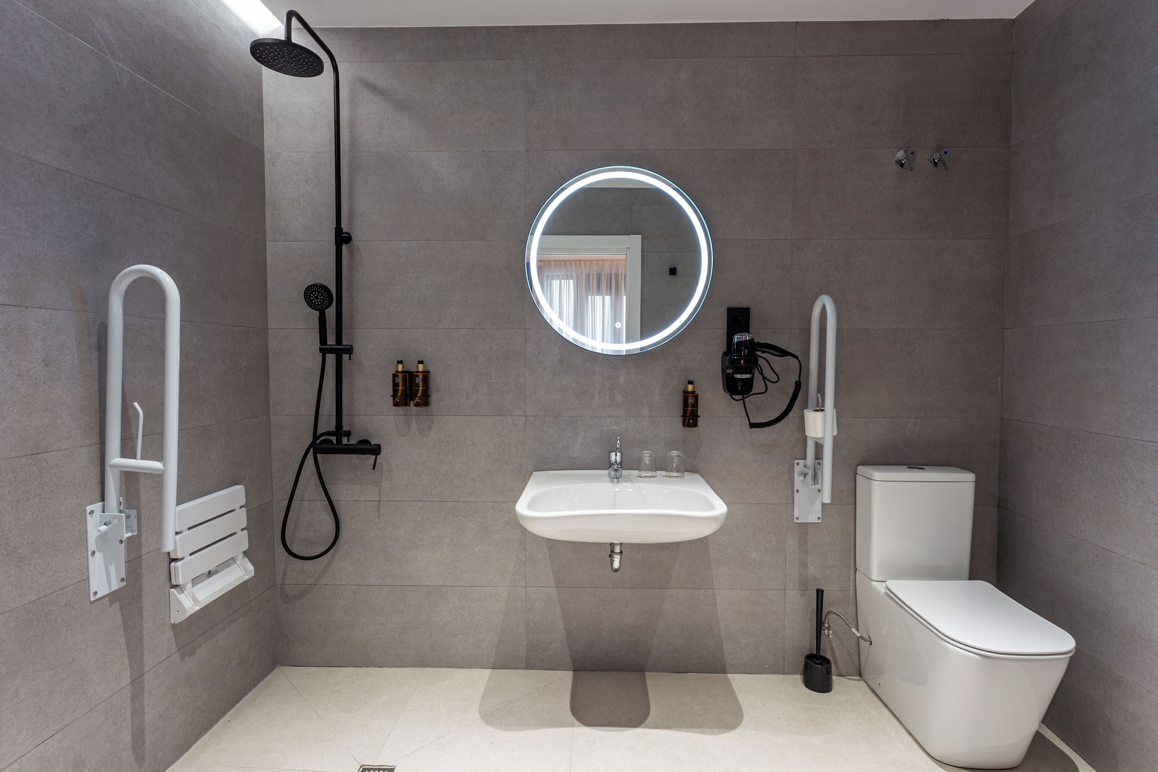 A modern bathroom with a shower, sink, toilet, and a mirror with a light.
