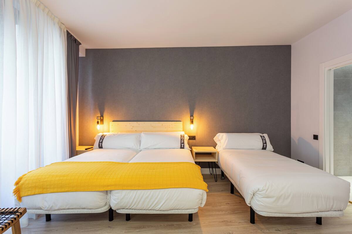 A hotel room with a large bed, a smaller bed, and a desk.