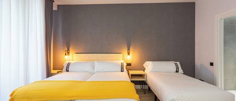 A hotel room with a large bed, a smaller bed, and a desk.