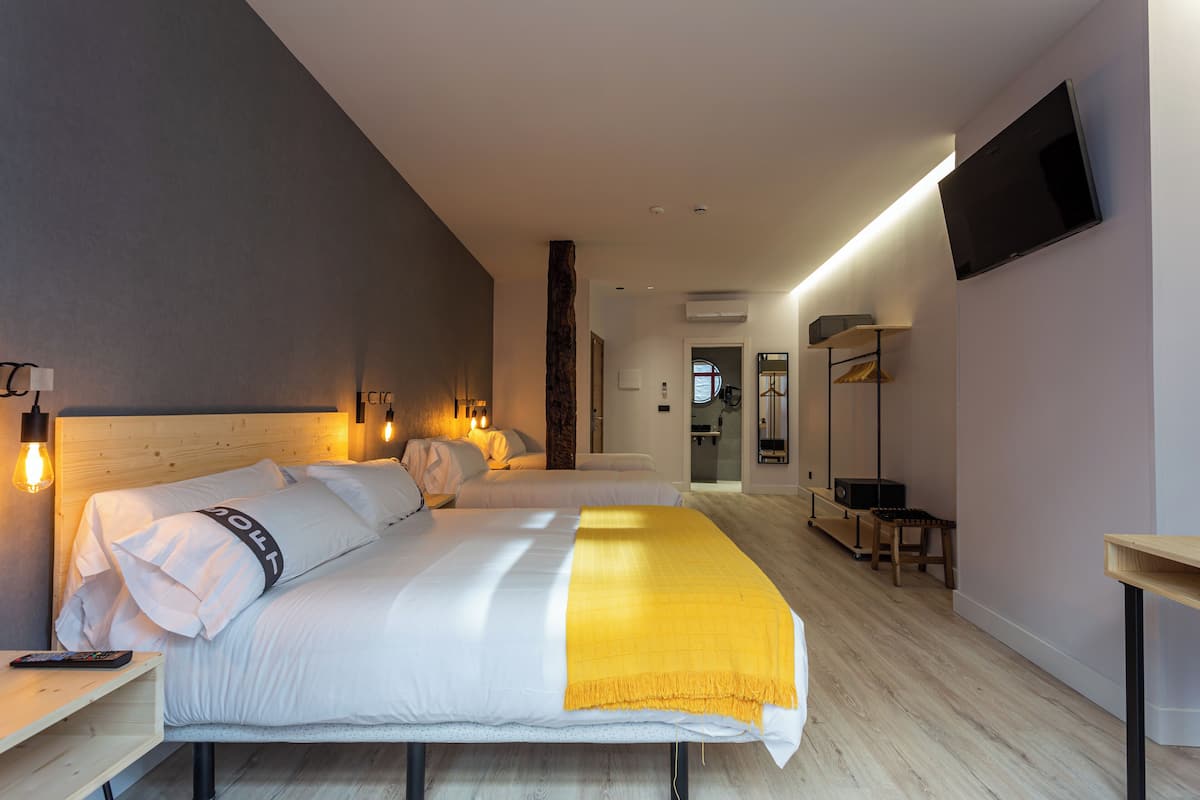 A modern hotel room with two beds, a TV, and a wooden floor.