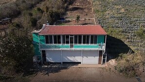 Um edifício de dois andares com telhado vermelho, varanda e garagem.