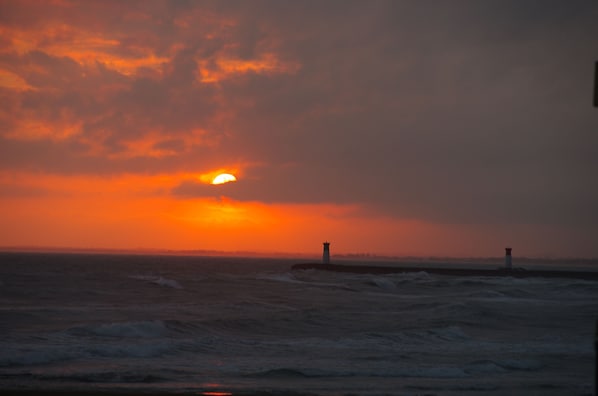 A sunset over the ocean with a lighthouse in the distance. - Sea side private mobil-home, large external terrace, private parking (Agde)