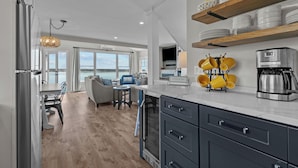 A modern kitchen with a built-in oven, a coffee maker, and a dining area with a view of the outdoors.