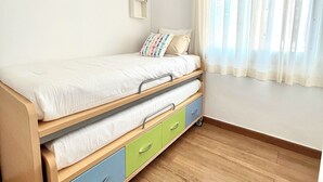 A single bed with storage drawers, a bedside table, and a window with sheer curtains. - Flat Tarajal SeaView in Mesa del Mar, Tacoronte Tenerife (CN)