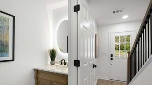 A hallway with a white door, a potted plant, a framed picture, and a marble countertop.