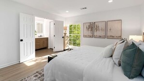 Un dormitorio con una cama grande, un vestidor y un ventanal con vistas a la vegetación.