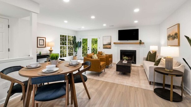 Una sala moderna con chimenea, un comedor con mesa redonda y una zona de estar con sofás.