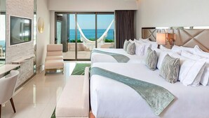 A hotel room with a large bed, a chair, a desk, and a view of the ocean.