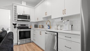Una cocina moderna con armarios blancos, electrodomésticos de acero inoxidable y lavavajillas.