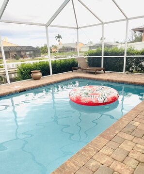 Relax by the tranquil pool, surrounded by lush greenery and a comfortable lounge chair.