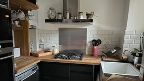 Eine moderne Küche mit Gasherd, schwarzem Geschirrspüler, Holz Arbeitsplatte und weiß gefliestem Fliesenspiegel.